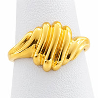 Vista frontal de anillo de oro con diseño de concha acanalada sobre exhibidor blanco.
