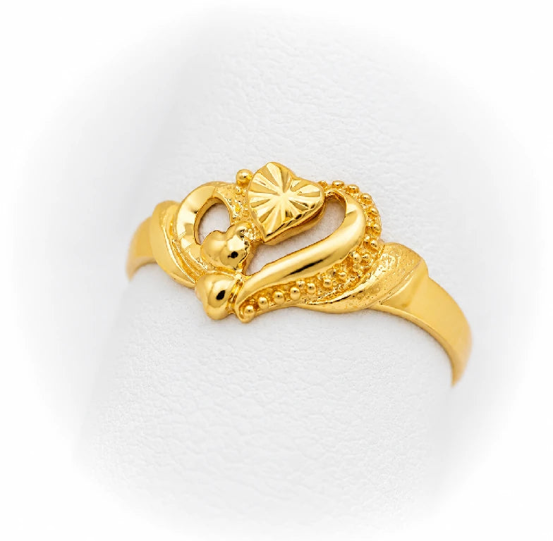 Anillo de oro amarillo con diseño de corazón calado y corazones en relieve, visto desde el lado izquierdo sobre exhibidor blanco.