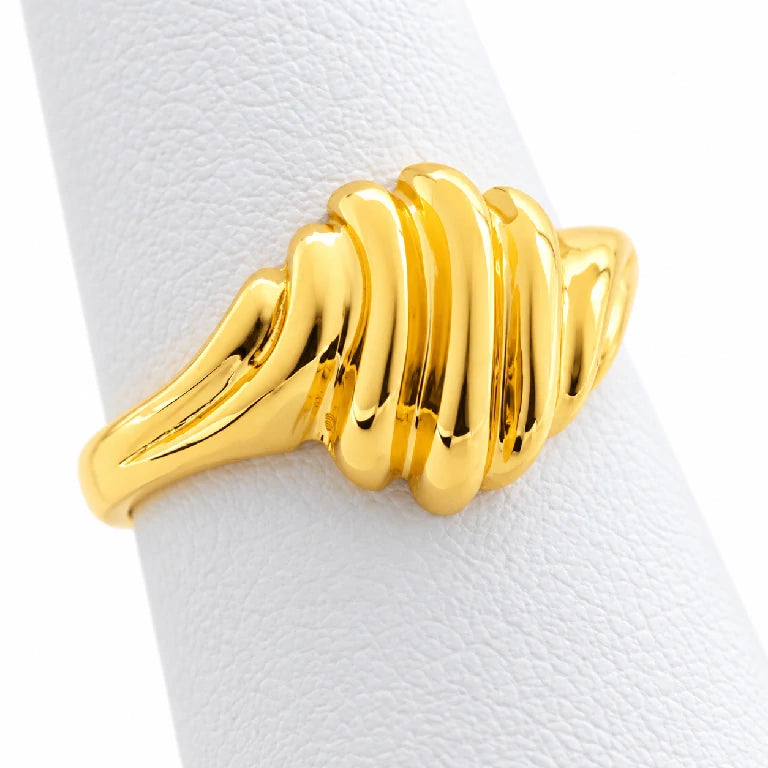 Anillo de oro estilo cúpula visto de lado, con relieves curvos y aro pulido sobre exhibidor blanco.