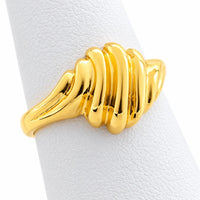 Anillo de oro estilo cúpula visto de lado, con relieves curvos y aro pulido sobre exhibidor blanco.
