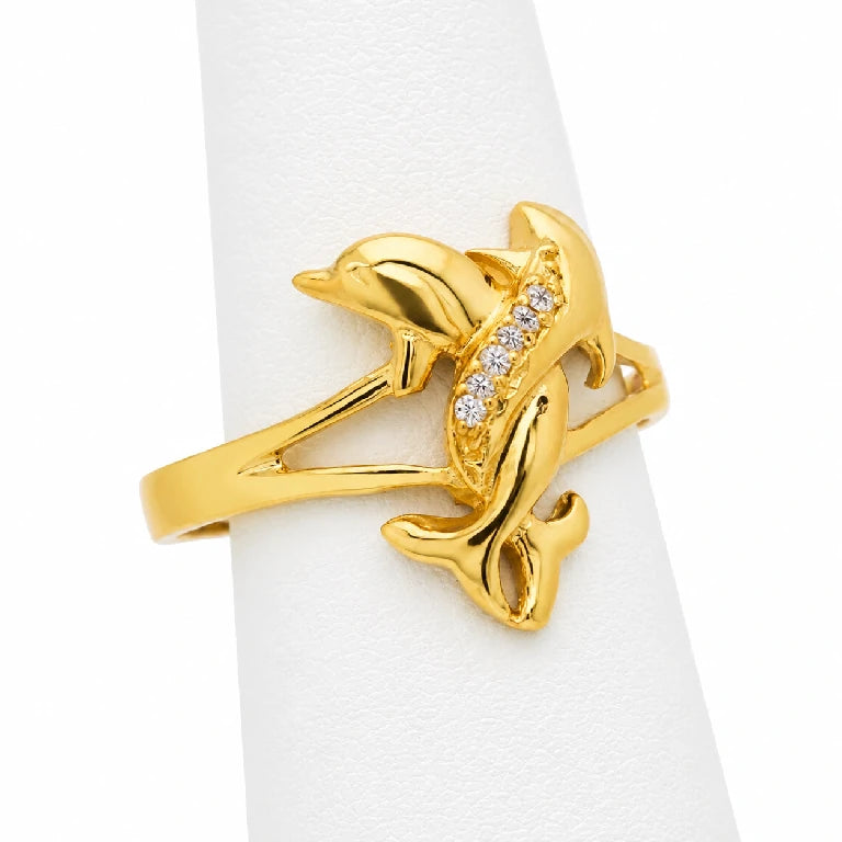 Anillo de delfines de oro 10k o 14k con circonias mostrado sobre exhibidor blanco