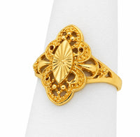 Anillo de oro amarillo con centro de almendra y líneas radiales, rodeado de calado tipo filigrana sobre exhibidor blanco.