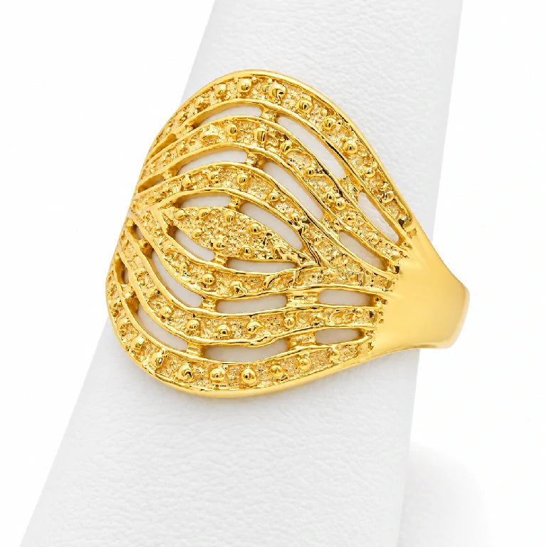 Anillo grande de oro amarillo sobre exhibidor blanco con diseño abierto y detalles decorativos brillantes.