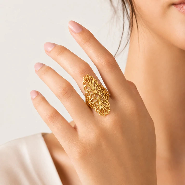 Joven usando anillo largo de oro 14k en el dedo medio con diseño calado elegante