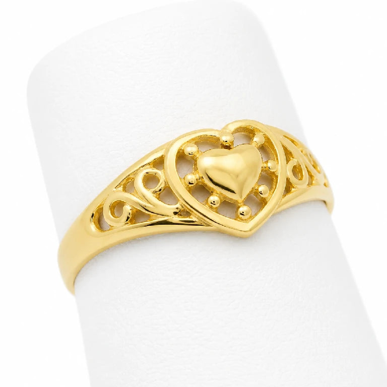 Anillo de corazón para mujer en oro 10k o 14k con diseño calado ornamental, mostrado en ángulo sobre exhibidor blanco.