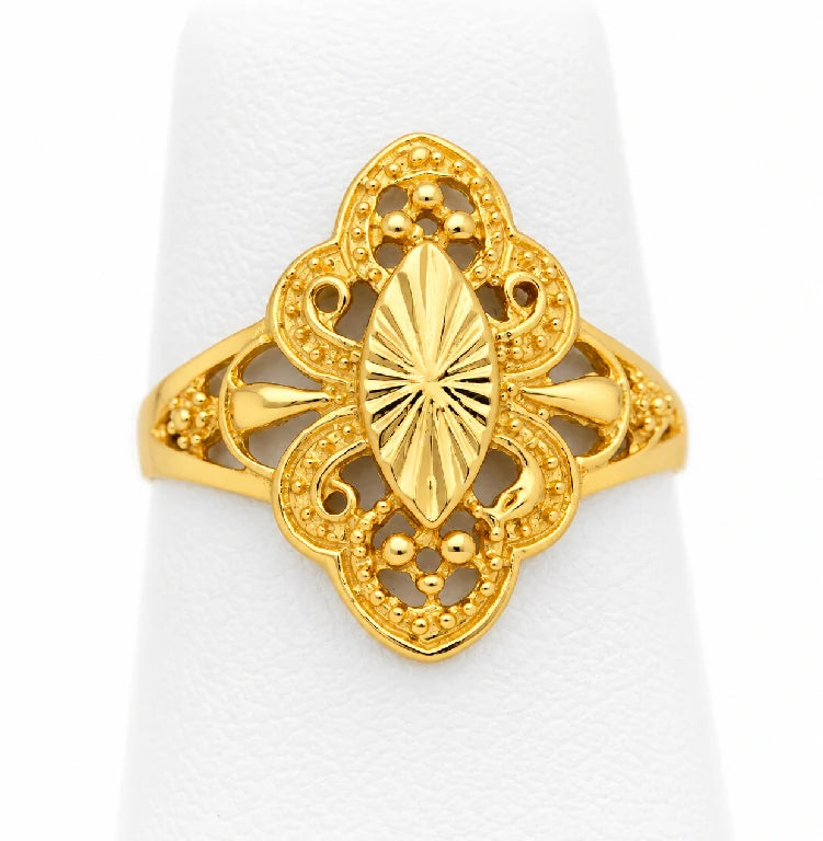 Anillo de oro amarillo con centro de almendra y líneas radiales, rodeado de calado tipo filigrana sobre exhibidor blanco.