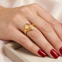 anillo de oro con 6 piedras rojas en el dedo de una mujer